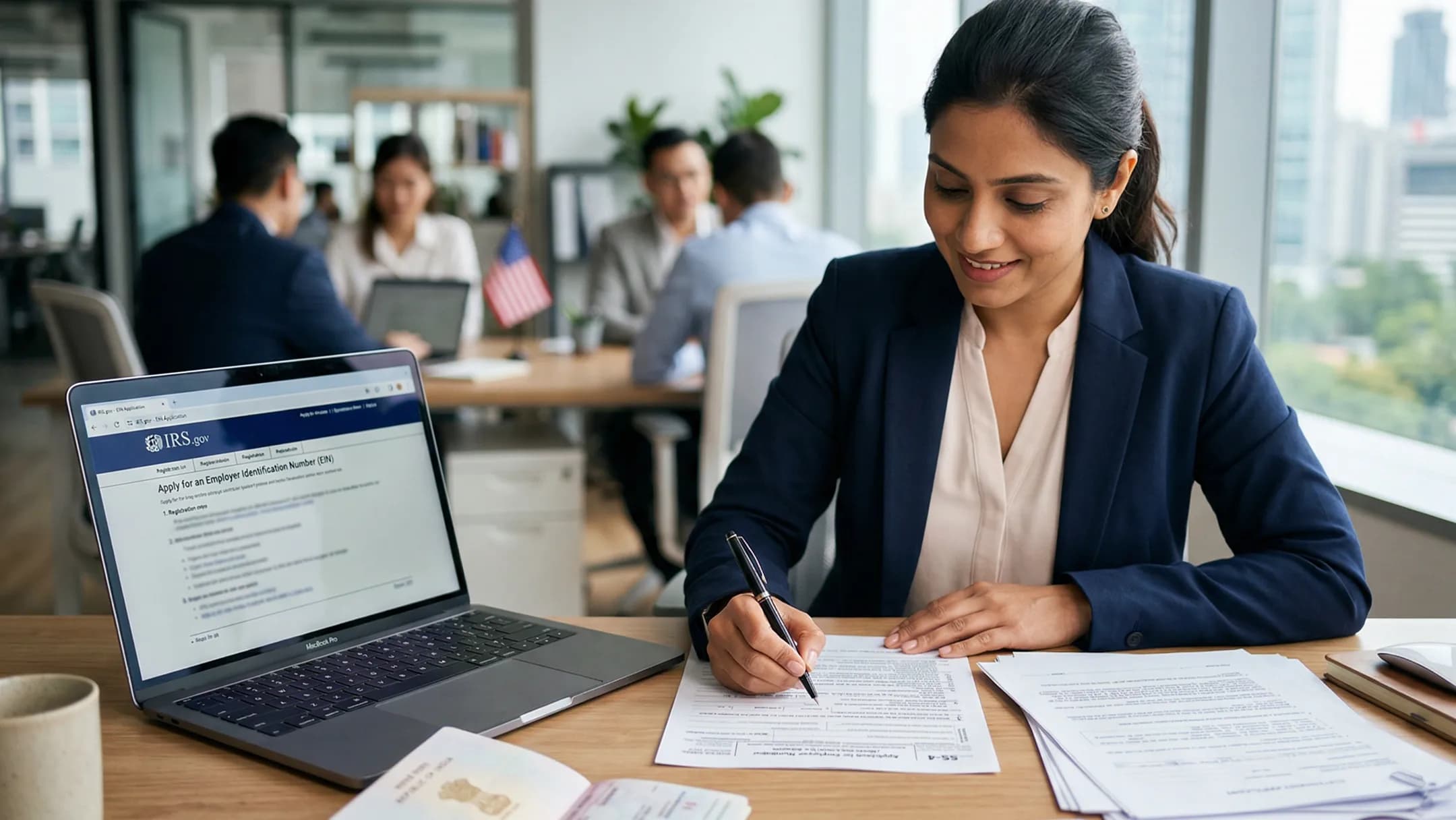 A businesswoman signing forms beside a laptop showing a government tax website in a modern office